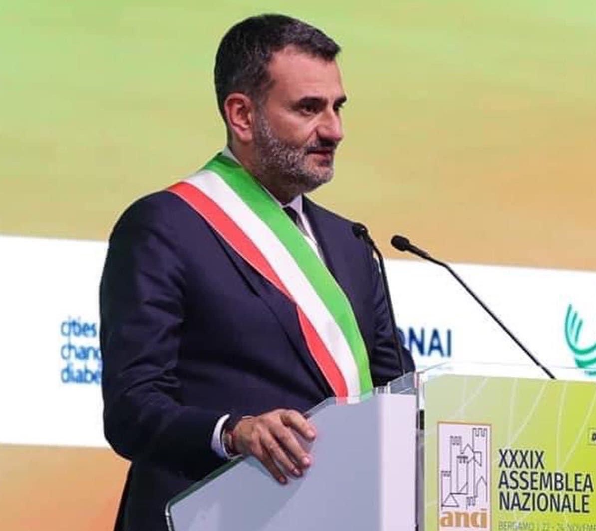 Il sindaco di Bari, Antonio Decaro su un pulpito tiene un discorso come presidente dell'Anci. Indossa la fascia tricolore sulla giacca nera
