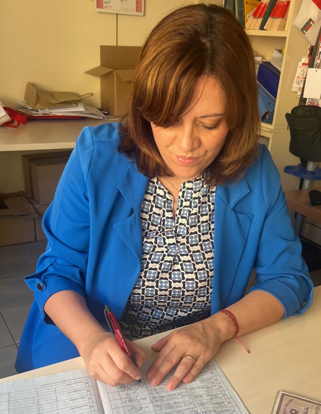 Una mia immagine mentre firmo per il referendum sul lavoro. Indosso una gaicca azzurra sopra una camicia a fantasia bianca, grigia e blu